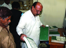 A tax collector reviews documentation from a citizen in Punjab, Pakistan A tax collector reviews documentation from a citizen in Punjab, Pakistan